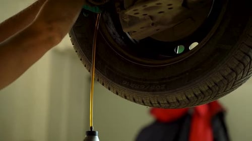 A Mechanic Pumps Brake Fluid Into the Brake Drums of a Car at a Service Center