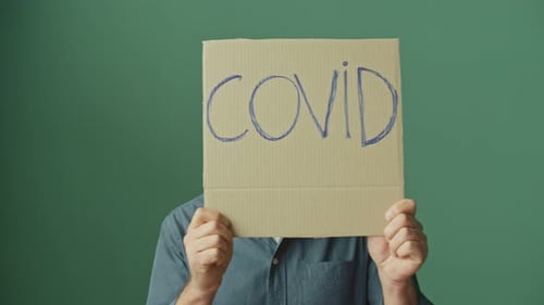 Adult with Mask Holds COVID Awareness Sign