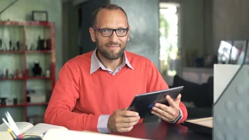 Happy young entrepreneur works on tablet at home in his modern apartment