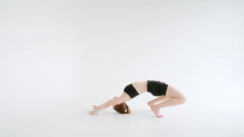 Mujer flexible realizando una postura de arco mirando hacia arriba durante una sesión de yoga avanzada
