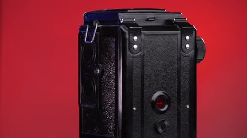 Closeup Vintage Old Photo Camera Rotates on a Red Pink Background