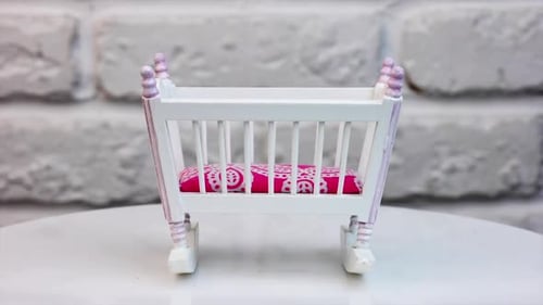 Beautiful toy cradle on a turning table. White baby crib made of wood