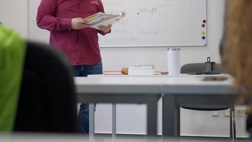 Teacher With Book Standing in Classroom