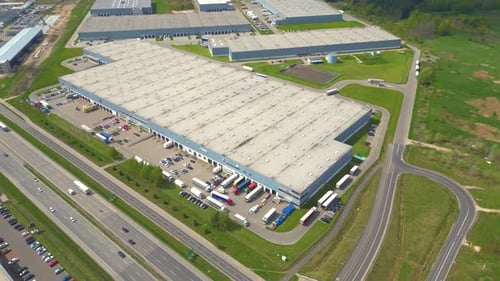 Aerial shot of industrial warehouse. Loading hub and many trucks with cargo trailers. Aerial view of