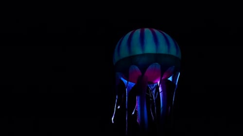 Blue jellyfish balloon illuminated at night during a parade