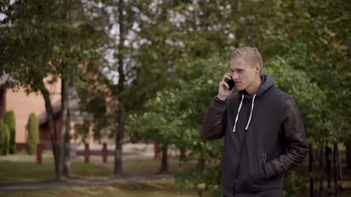 Young Man Talking on Phone in a Park