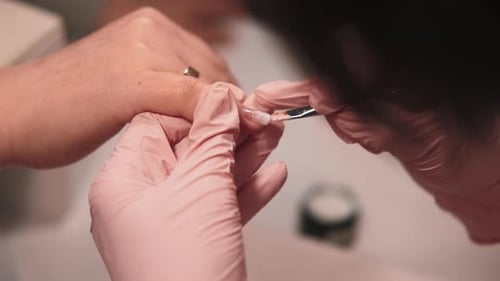 Woman Receiving Manicure from Technician in Salon