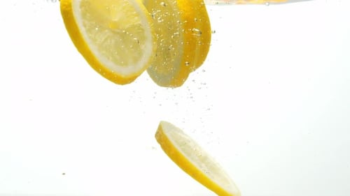 Lemon Slices Falling Into Water Creating Bubbles