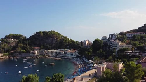 Drone shot revealing a beautiful, tranquil bay in Taormina, Sicily with resorts, hotels, apartments