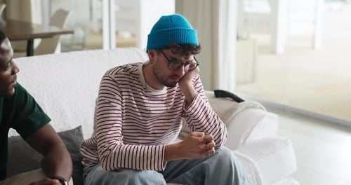 Two Men Talking on White Couch Indoors