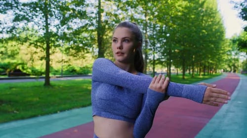 Young caucasian woman stretching before jogging in the park. Shot with RED helium camera in 8K.