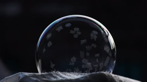 Um padrão de gelo cobre a superfície lisa de uma bolha de sabão transparente