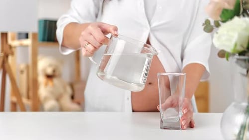 Nicht wiederzuerkennende schwangere Frau trinkt frisches reines Wasserglas Genießen Sie einen gesunden Lebensstil zu Hause