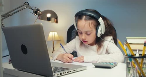 Little Schoolgirl Wearing Headphones Studying Online School With Tutor