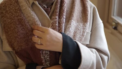 Woman Adjusts Scarf in Beige Winter Outfit