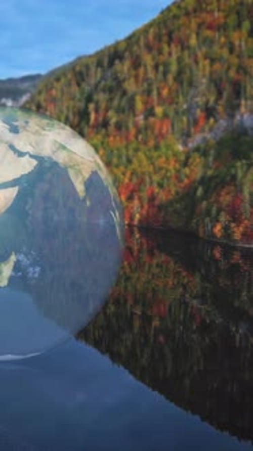 Animated floating globe over a reflective autumn lake with vibrant hills nearby