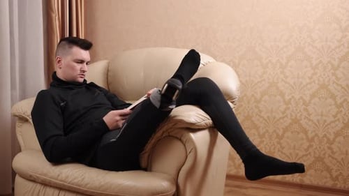 Young Adult Relaxing on Couch Reading Book
