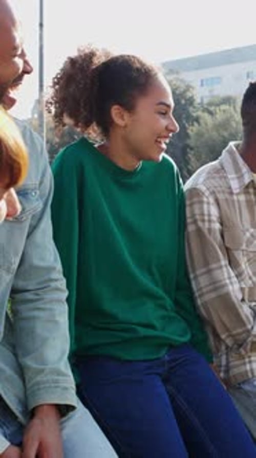 Young Adults Laughing and Chatting Outdoors in Sunshine