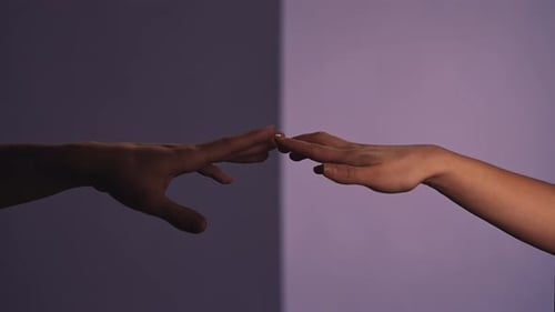 Man and Woman Touching Hands and Crossing Fingers Isolated on Purple Studio Background Close Up Shot