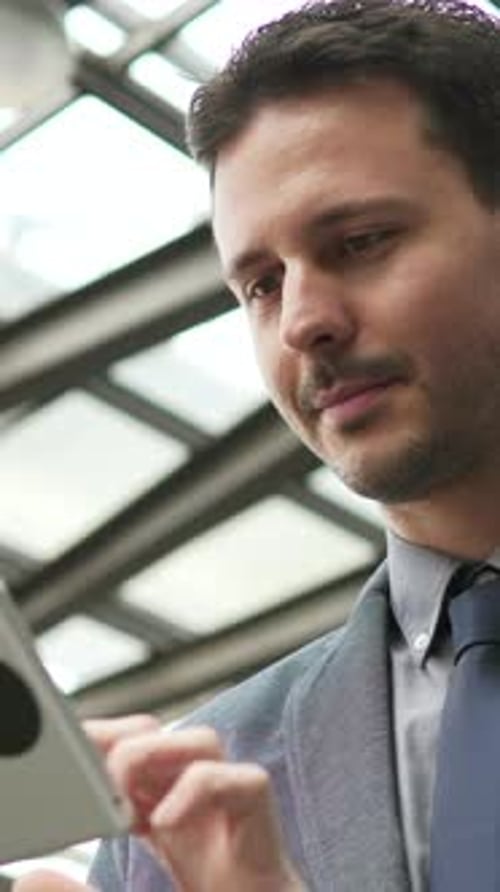 A Businessman Actively Engaged While Using a Tablet in a Contemporary Office Environment