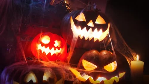 An ominous mountain of smoking orange carved pumpkins with multi-colored lights