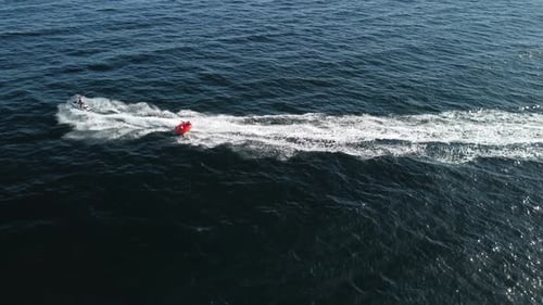 Jet Ski Towing Raft Across Sparkling Ocean
