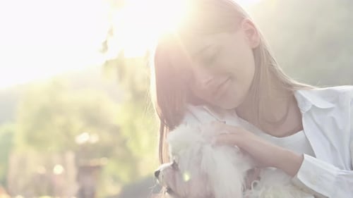 Young Woman Cuddling with Dog in a Park