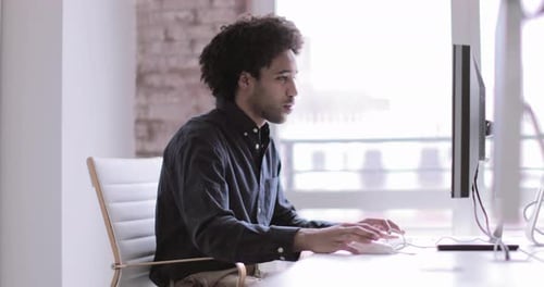 Male african american business executive working in an office on a desktop computer