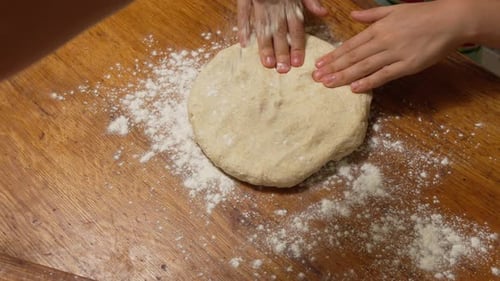Hands Shaping a Dough on a Wooden Board