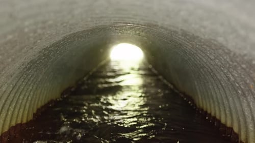 Regenwasser fließt durch gewelltes Regenwasserabflussrohr, Sockelschuss