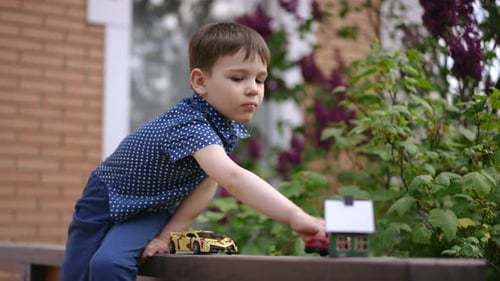 Young Boy Playing With Toy Cars Outside Home