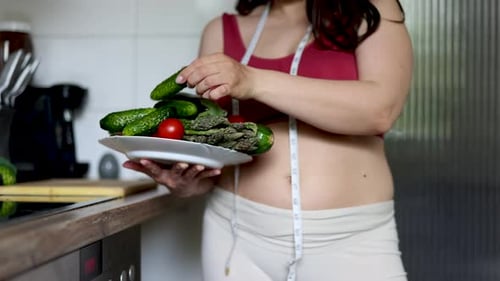 Woman Holds Plate of Vegetables in Kitchen