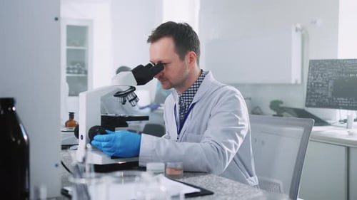 Focused Scientist Working with Microscope in Bright Lab