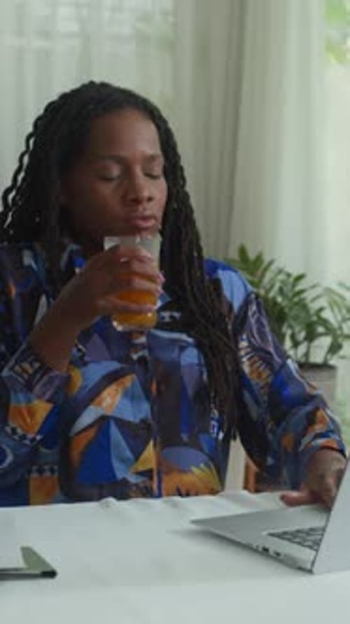 Woman Working at Table, Drinks Juice
