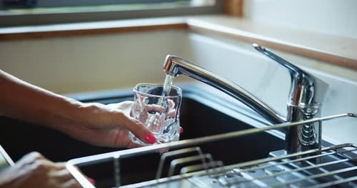 Woman Filling Glass with Water at Sink