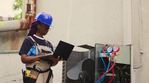 HVAC Technician with Laptop Checks Air Conditioner
