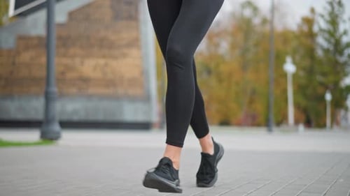 Closeup View of Athletic Woman Running on Street Path in Black Leggings and Sneakers