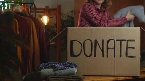 Young Adult Packing Clothing into a Donation Box