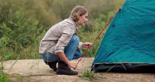 Woman, campsite and camping with tent outdoors, nature and survival or adventure with shelter setup
