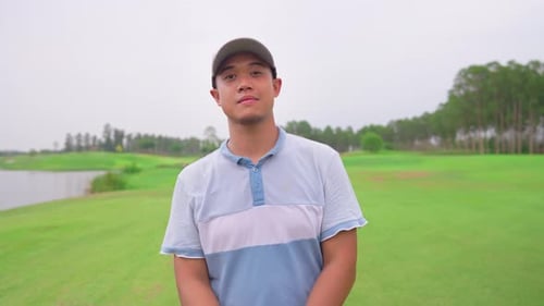 Portrait of young male golfer holding club on scenic golf course.