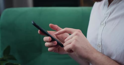 Primer plano de las manos de un joven irreconocible escribiendo el teléfono inteligente y presionando la pantalla.