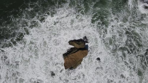 Aerial view of giant ocean waves crashing and foaming in coral beach