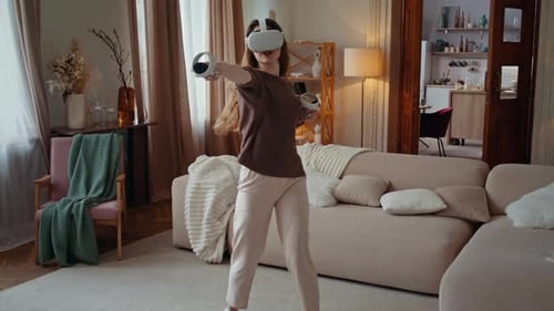 Woman Plays VR Game in Living Room with Hand Controllers