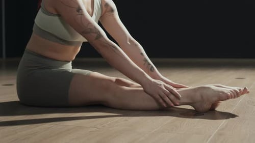 Fit Woman Balancing and Stretching on Wooden Floor