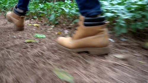 Hiker walks along a trail in the forest - low angle view showing just her boots along the path