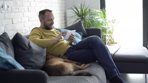Bearded man relaxing on the couch with tablet