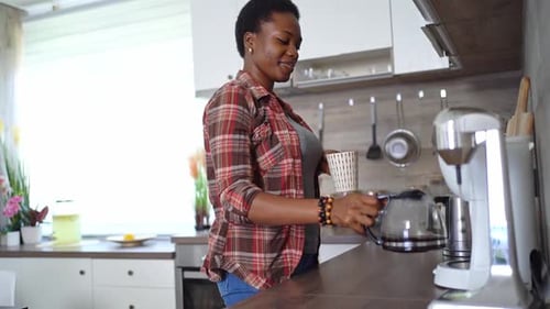 Woman Pours Herself Coffee in Bright Kitchen