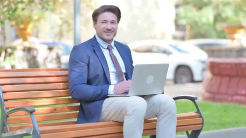 Man Working on Laptop in Urban Park