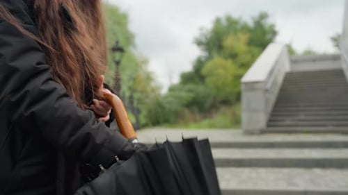 Woman Opens a Black Umbrella Near Concrete Stairs