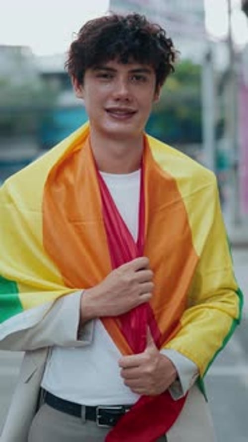 Young Adult Posing with Pride Flag on City Street